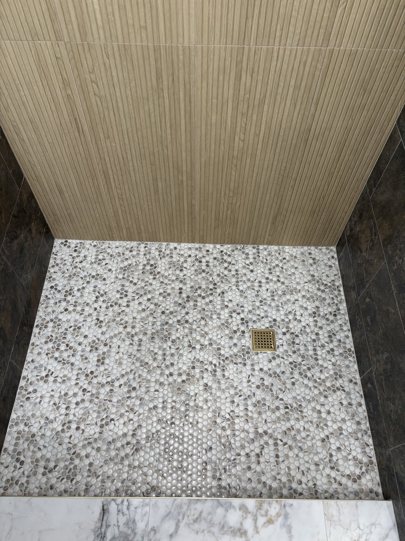 Custom shower with hexagon penny tile, reeded wood accent wall, and dark marble flooring β Coral Springs bathroom remodel